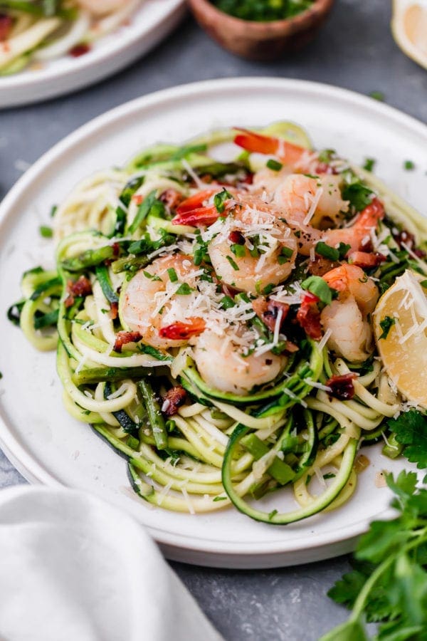 A plate filled with zucchini 'noodles' topped with shrimp, asparagus, and parmesan cheese!