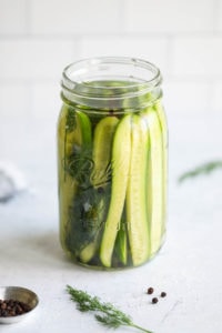 A quart jar filled with cucumber spears in vinegar for easy refrigerator pickles.