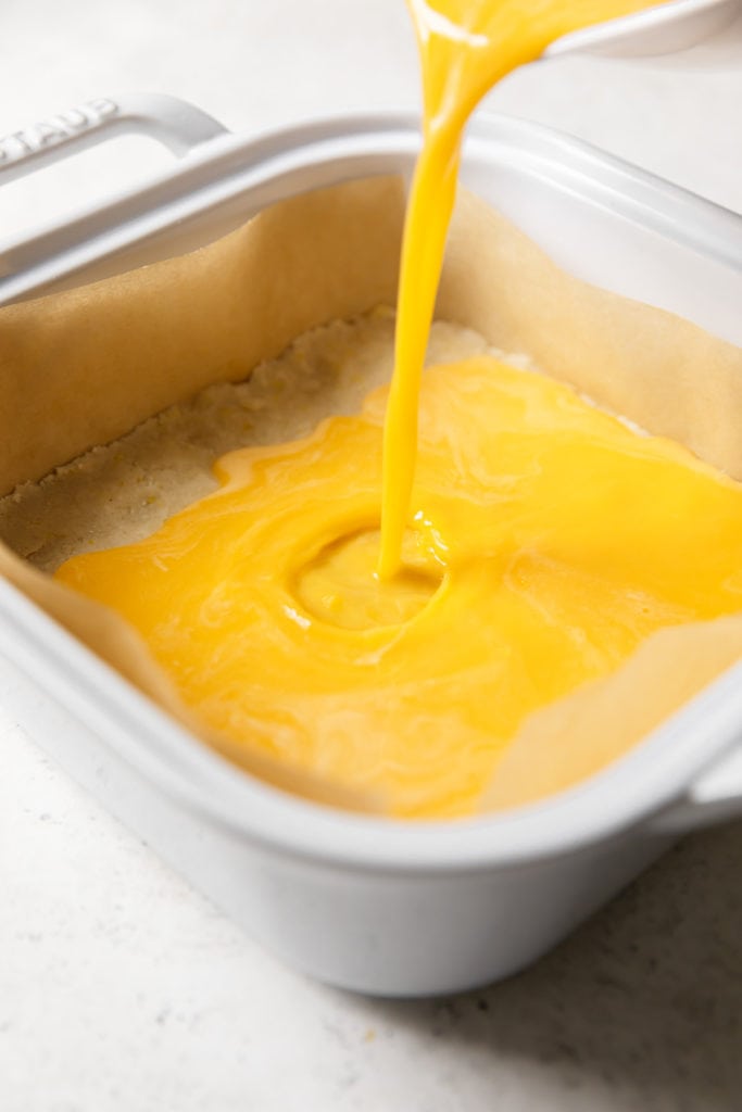 The lemon filling for gluten-free lemon bars being poured into a baking dish
