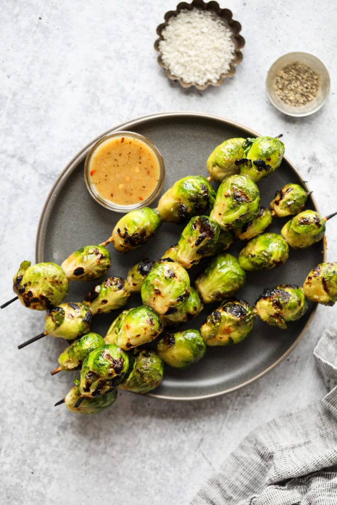 Five skewers filled with grilled Brussels Sprouts coated in a light layer of maple-mustard sauce