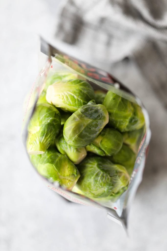 An overhead view of a bag of fresh Brussels Sprouts