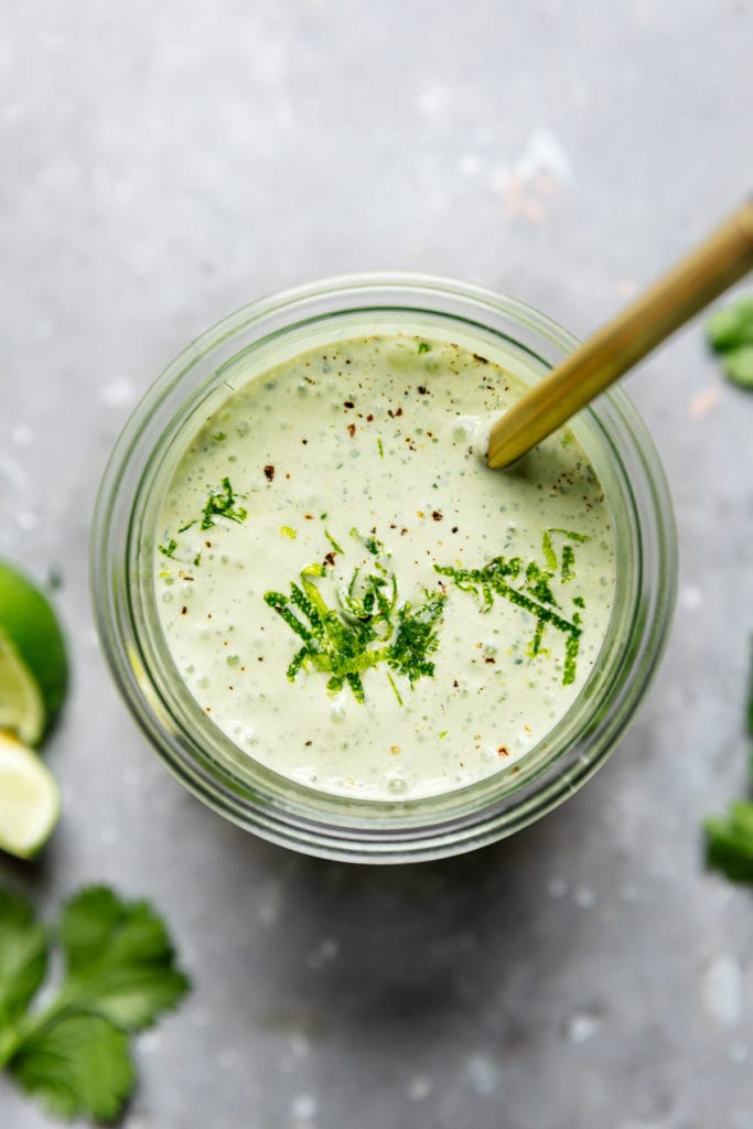 Cilantro-Lime Crema in the mason jar with a gold spoon, garnished with lime zest. 