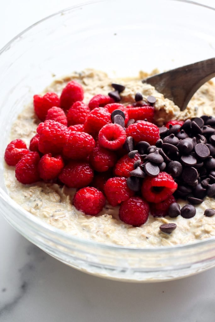 Raspberry chocolate chip baked oatmeal batter being stirred in mixing bowl with wooden spoon