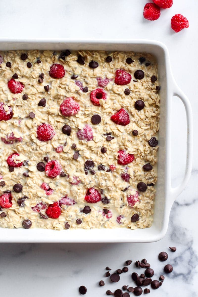 Raspberry baked oatmeal in a white baking dish topped with chocolate chips