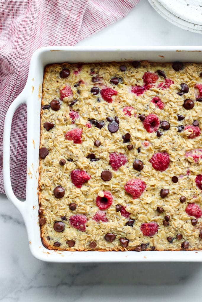 Raspberry baked oatmeal topped with chocolate chips in a white baking dish