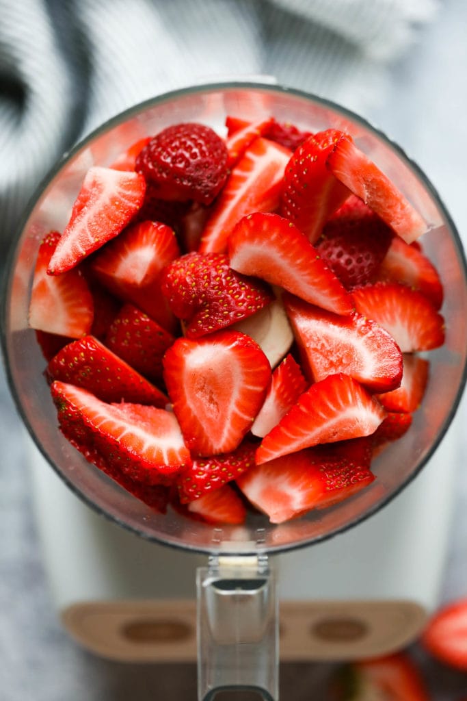 A food processor filled with cut fresh strawberries