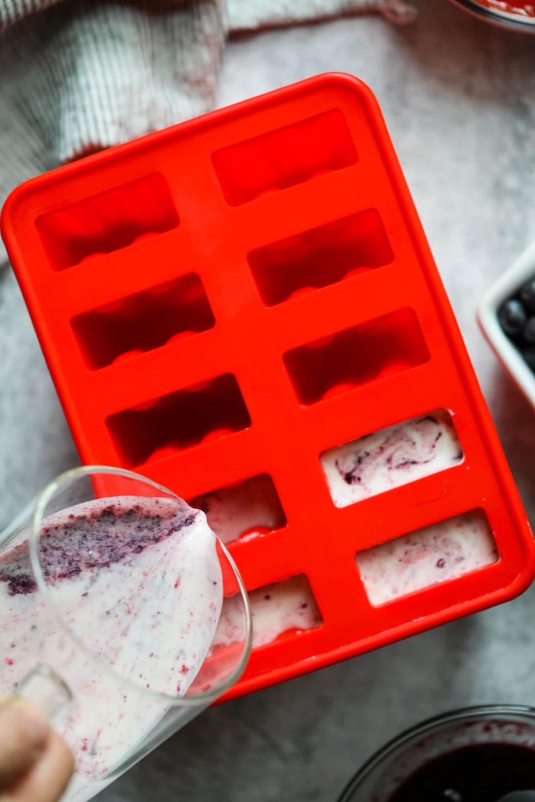 The mixture for homemade yogurt popsicles being poured into a popsicle mold