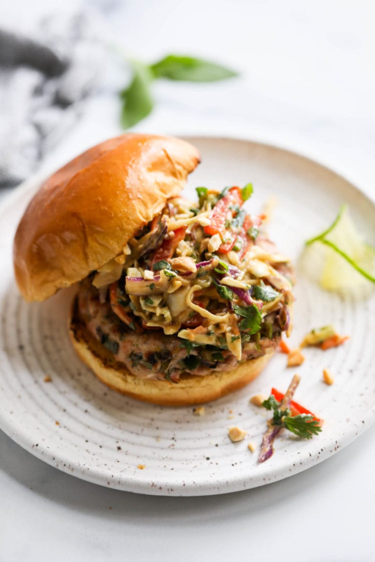 A grilled pork burger topped with creamy Thai Slaw in a gluten-free bun