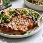 A juicy grilled pork chop marinated in homemade honey mustard marinade plated next to a side of coleslaw