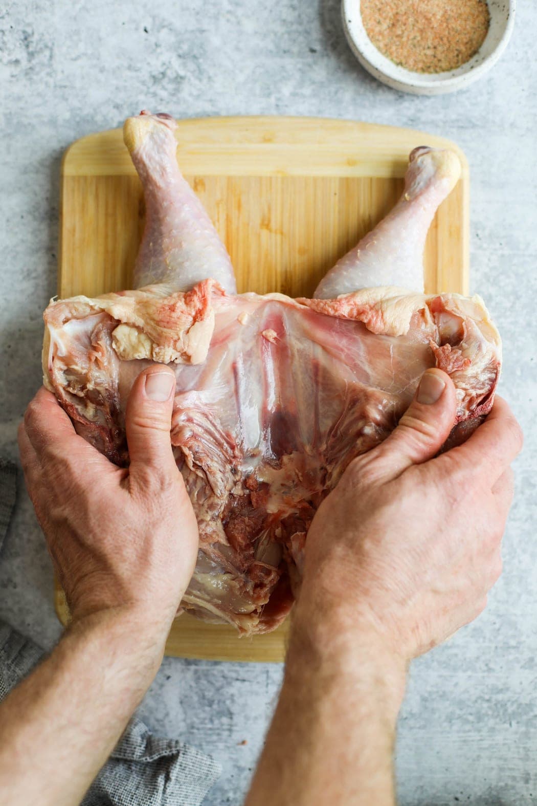 Two hands pressing a spatchcock chicken down