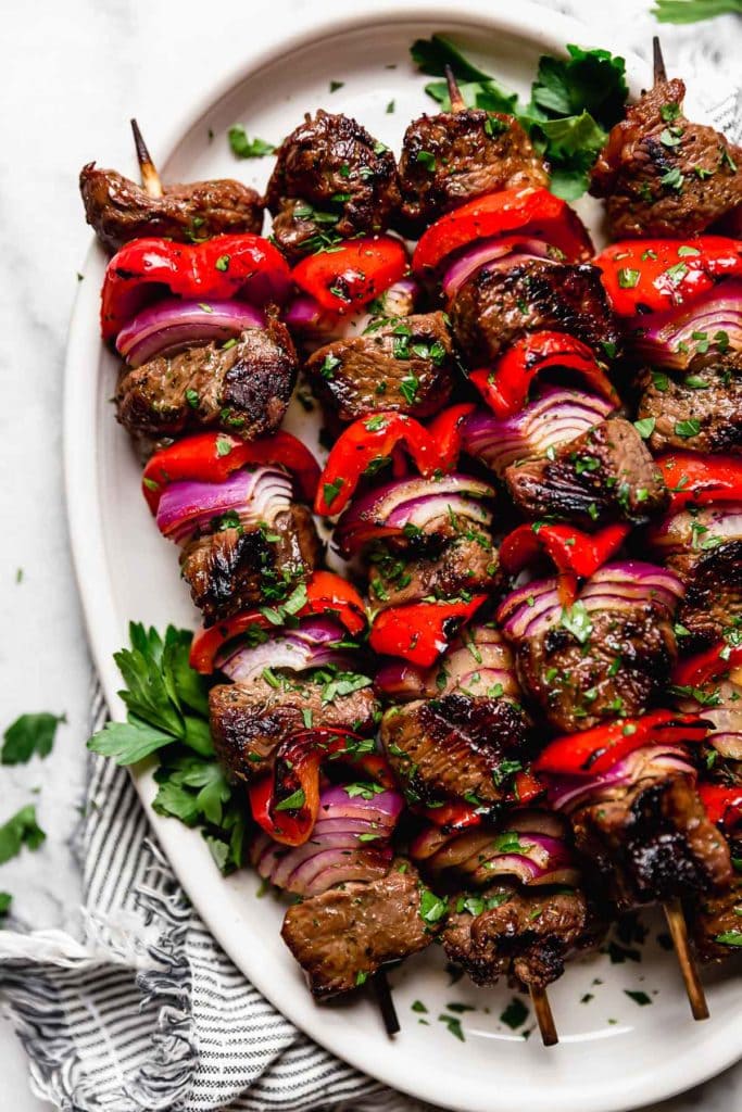 Easy Steak and Veggie Kebabs on skewers fresh from the grill on a white serving platter