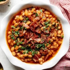 Instant Pot Baked Beans with bacon served in a white bowl with a red striped dish cloth next to the bowl