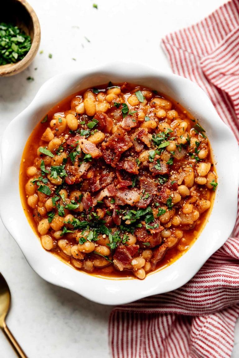 Instant Pot Baked Beans with bacon served in a white bowl with a red striped dish cloth next to the bowl