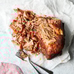 Smoked pork butt partially shredded on white parchment on a countertop