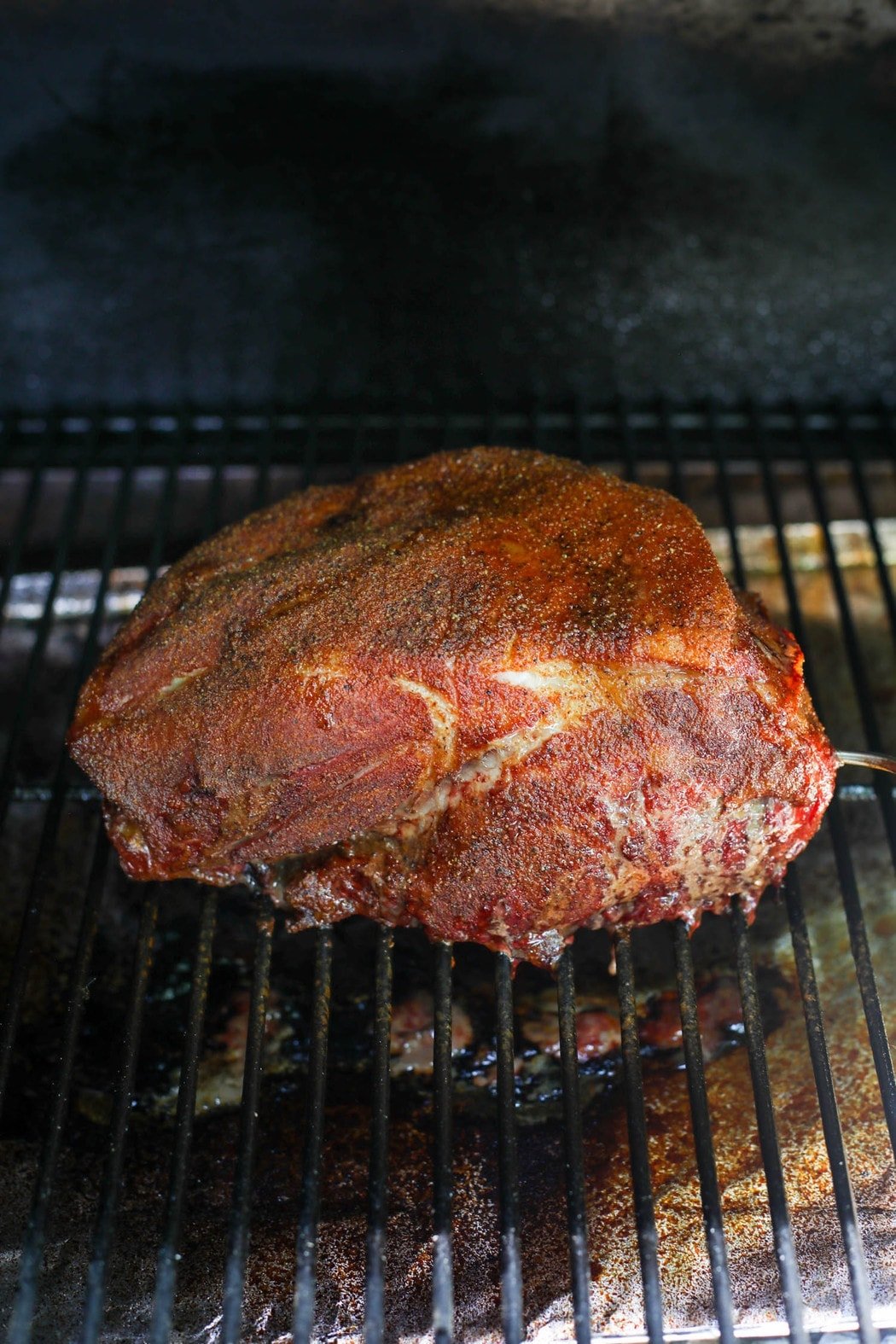 Smoked Pork Butt on grill grates being cooked 