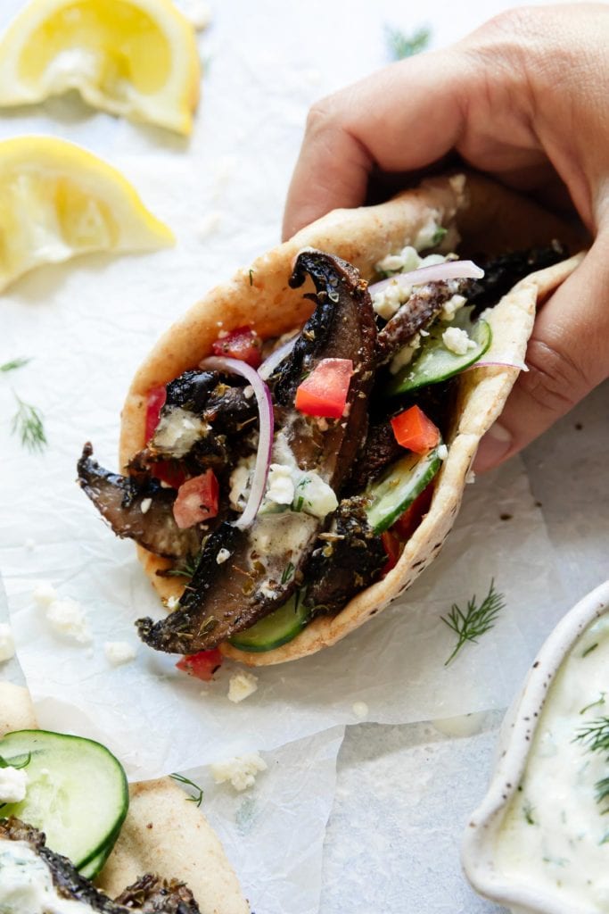 A gluten-free gyro stuffed with portobello mushrooms and tzatziki sauce wrapped and being held