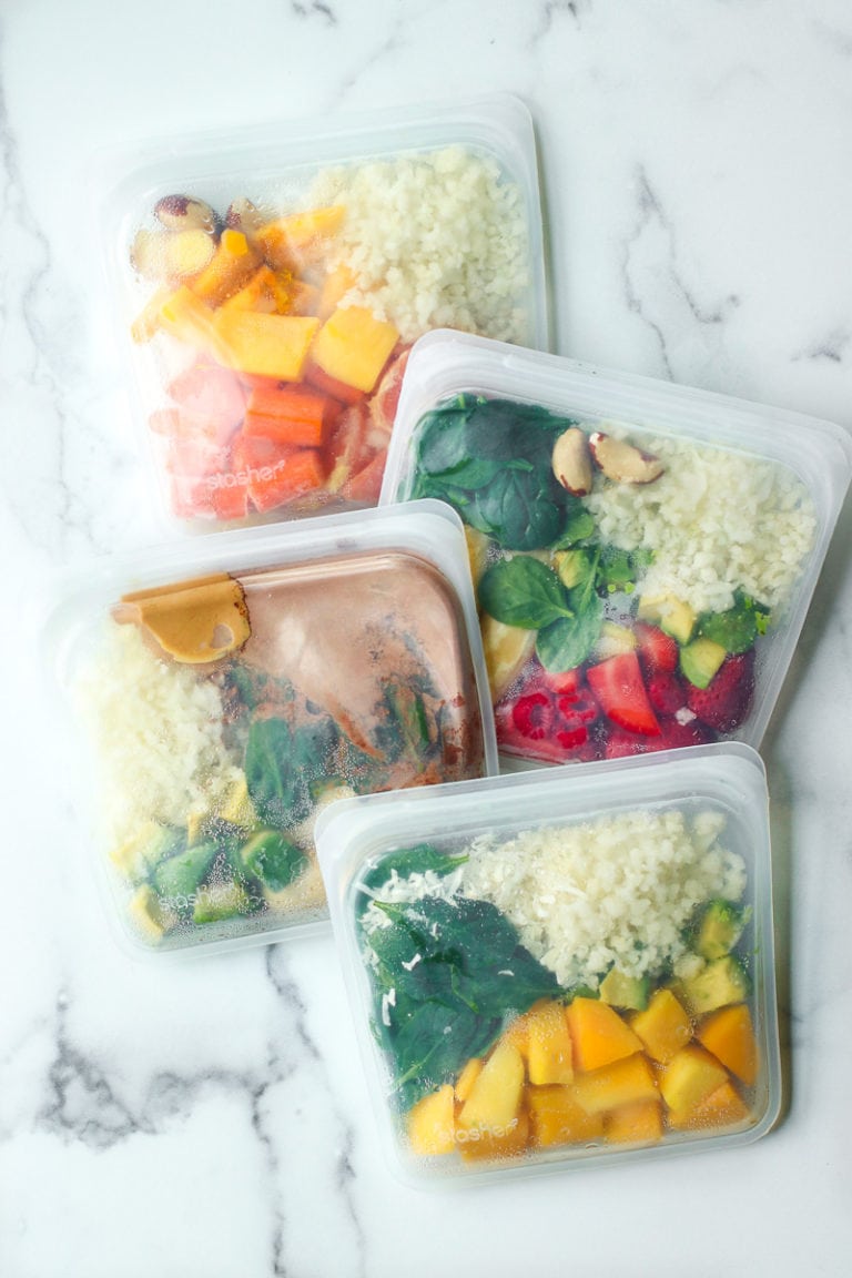 Four freezer bags filled with ingredients to make Healthy Make-Ahead Frozen Smoothie Packs. 