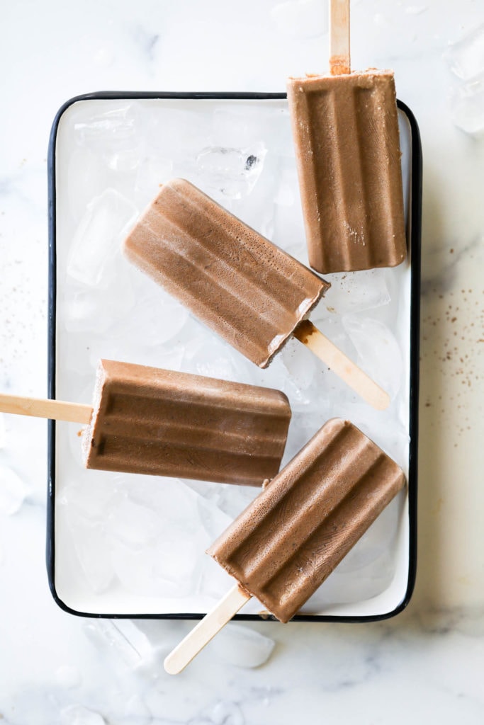Four creamy dairy-free fudge pops on ice in a serving tray