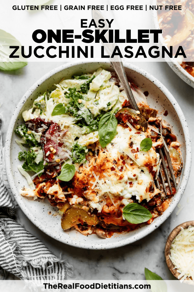 Zucchini lasagna topped with cottage cheese and mozzarella cheese plated on a speckled plate with a side of caesar salad.