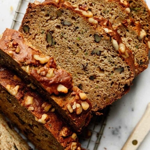 Thick slices of gluten free zucchini bread cut and lined up on a metal cooling rack