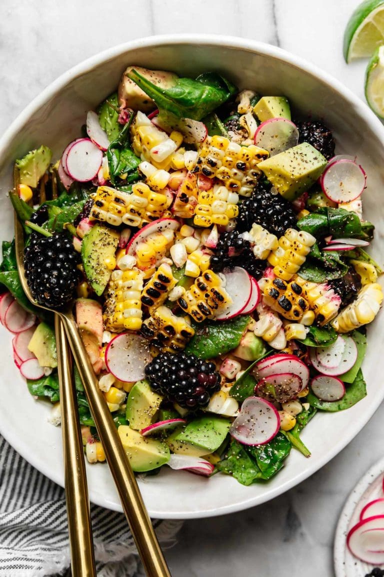 Overhead view grilled corn salad in white bowl topped with blackberries