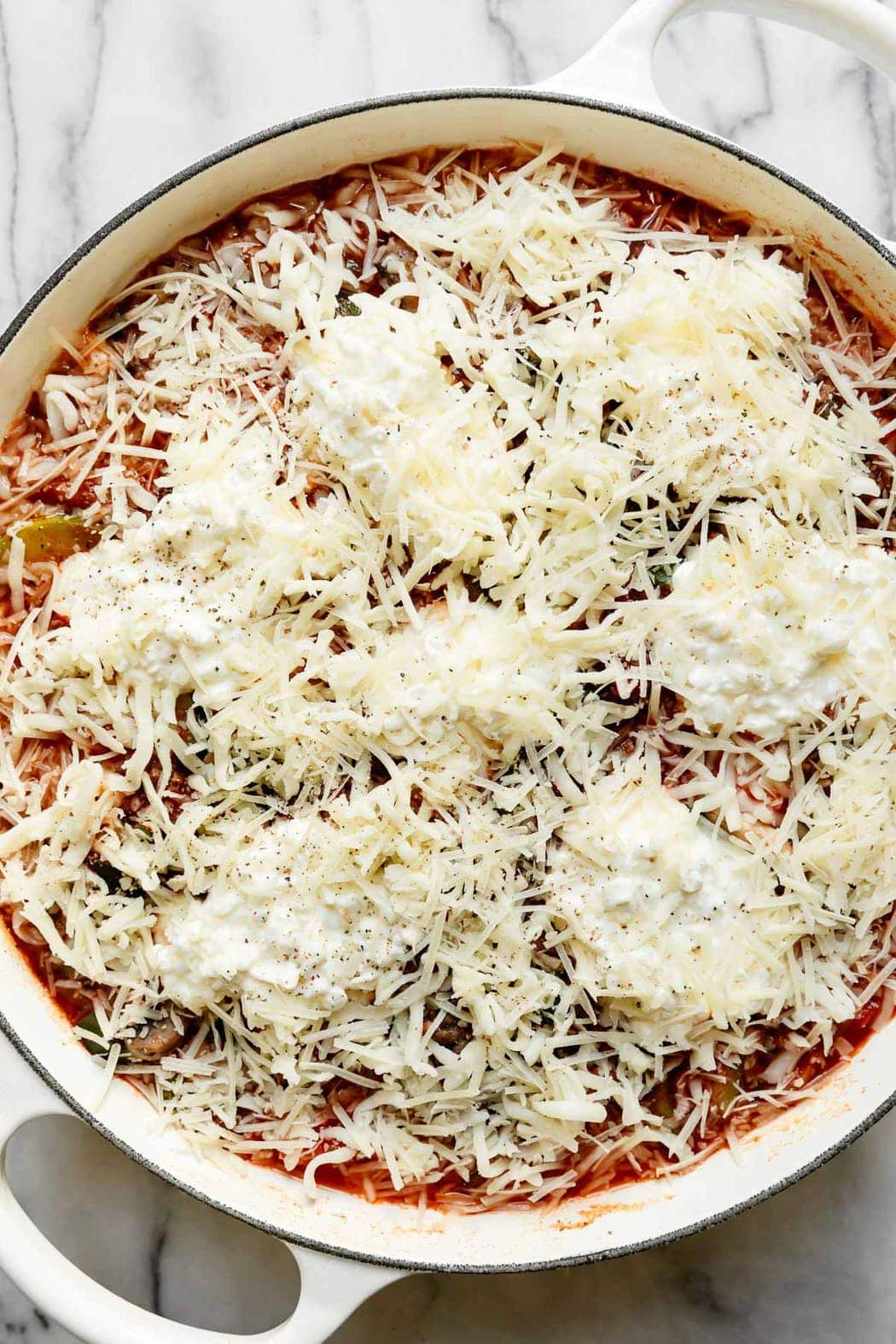 One-skillet zucchini lasagna freshly topped with mozzarella and parmesan cheese ready to start cooking. 