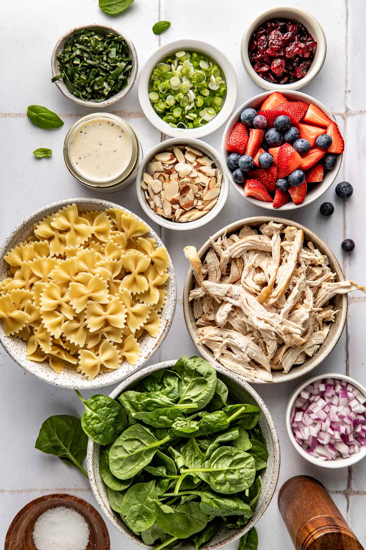 Overhead view of a variety of ingredients for Summer Berry Pasta Salad in different sized bowls. 