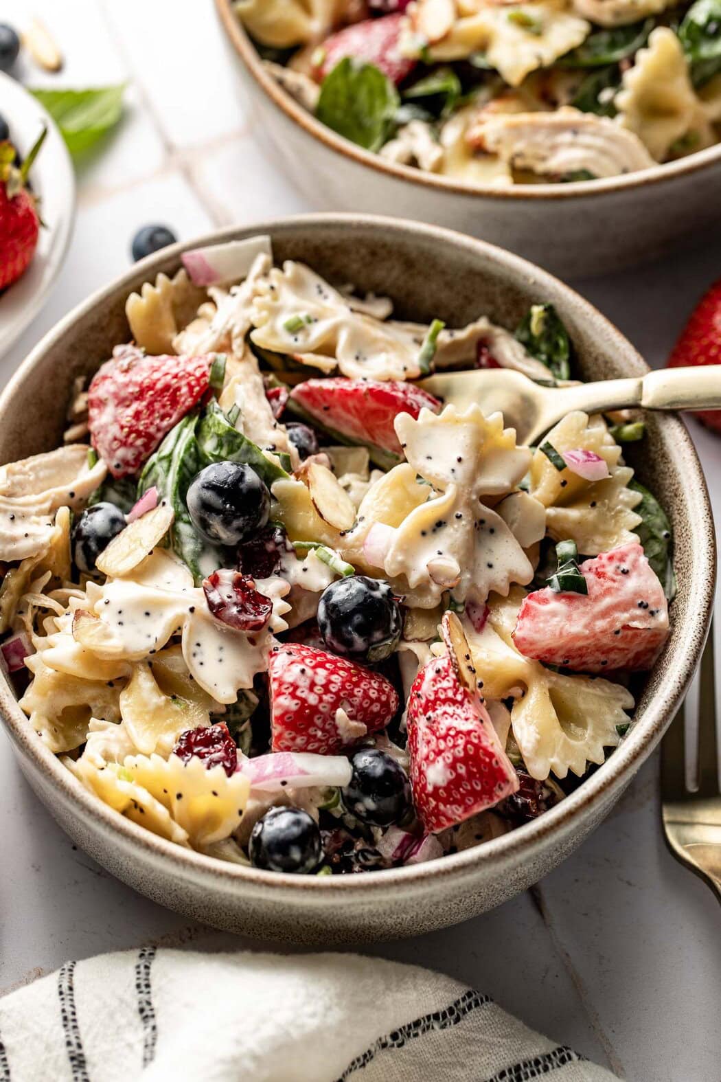 Close up view of a white bowl filled with Summer Berry Pasta Salad With Chicken.