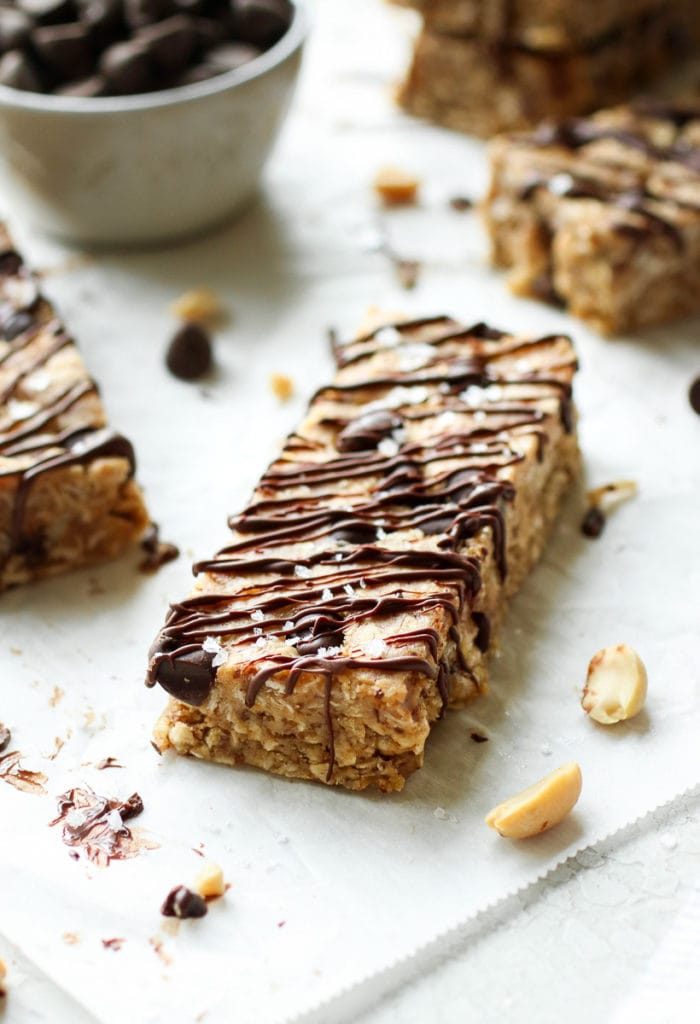 A homemade vegan protein bar laying on parchment paper and drizzled with chocolate