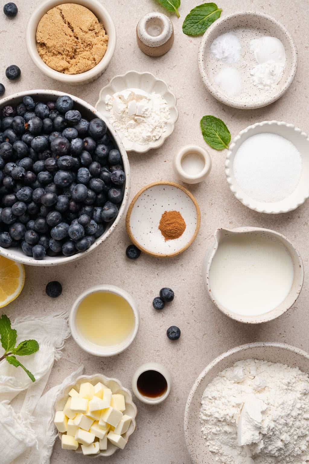 Overhead view of a variety of ingredients for Blueberry Cobbler in different sized bowls.
