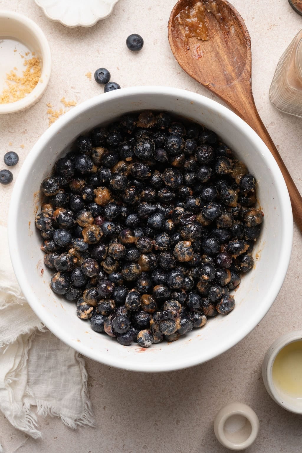 Overhead view of a white bowl of Blueberry Cobbler mixture ready for a baking dish.