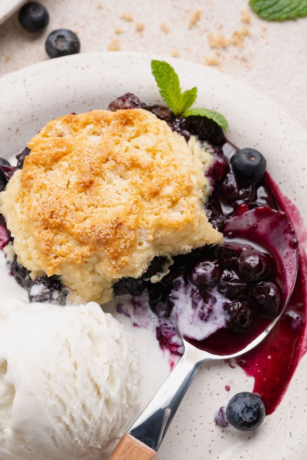 Close up view of a dish of Blueberry Cobbler with ice cream on the side.