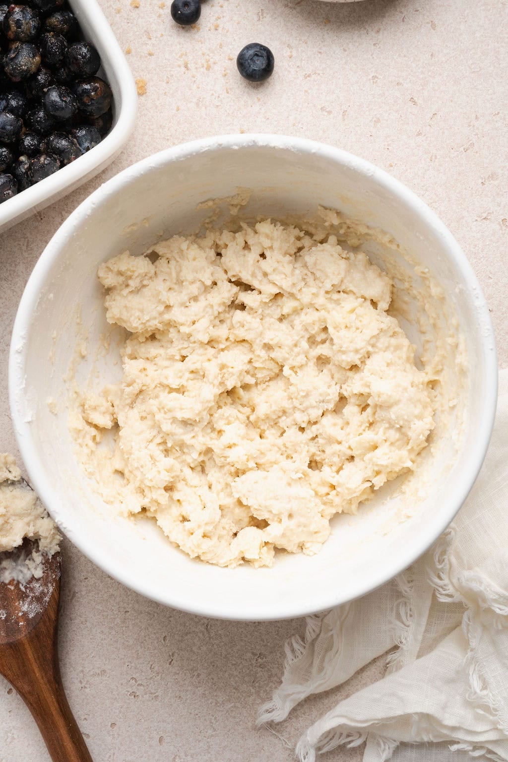 Overhead view of a white bowl filled with Blueberry Cobbler topping mixture. 