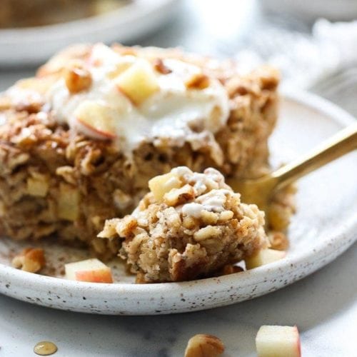 A slice of apple cinnamon baked oatmeal topped with yogurt on a plate.