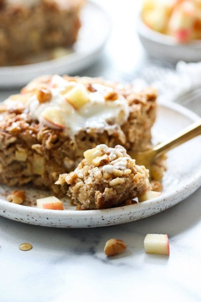 Soft and chewy apple cinnamon baked oatmeal plated on a speckled plate with a fork full ready to eat