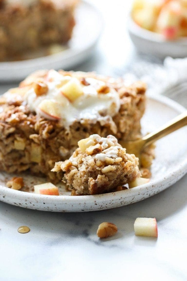 Close up side view piece of apple cinnamon baked oatmeal on stone plate with bite on fork