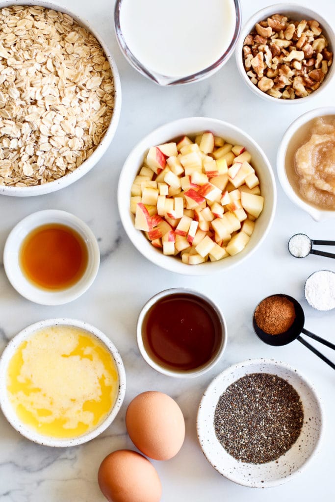 All ingredients for apple cinnamon baked oatmeal in small bowls and measuring cups. 