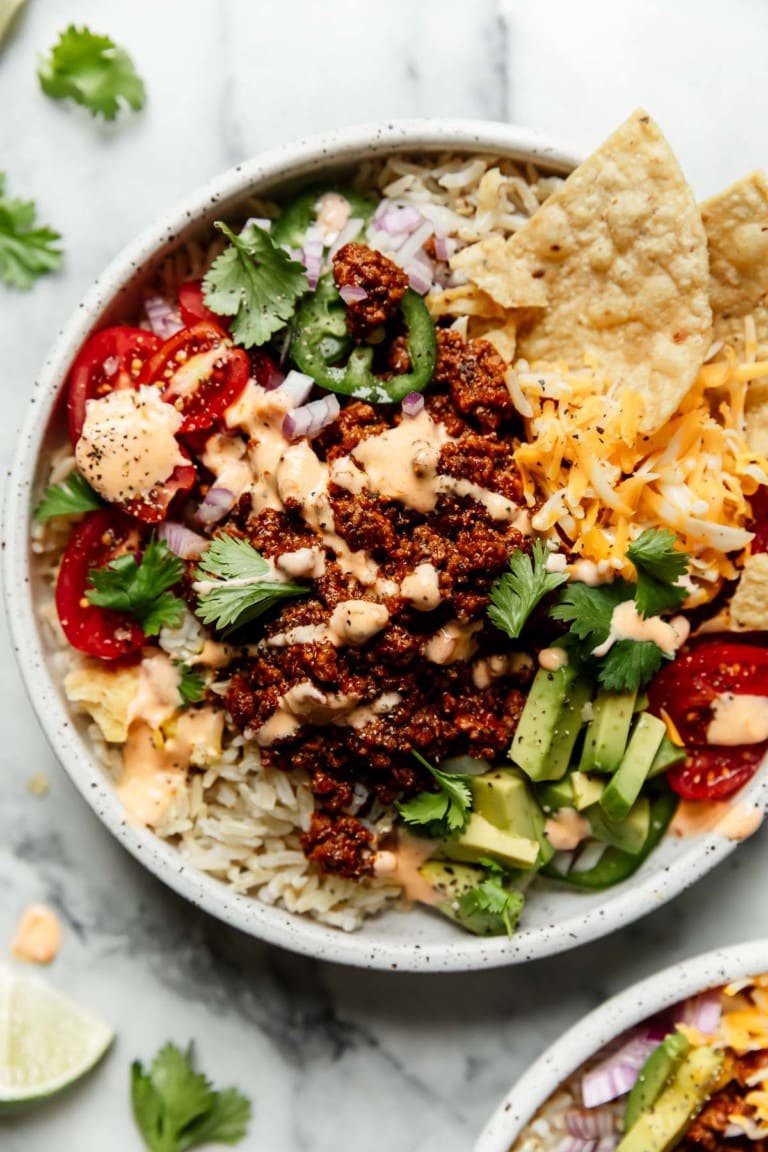 White bowl filled with beef taco mixture and veggies and rice.