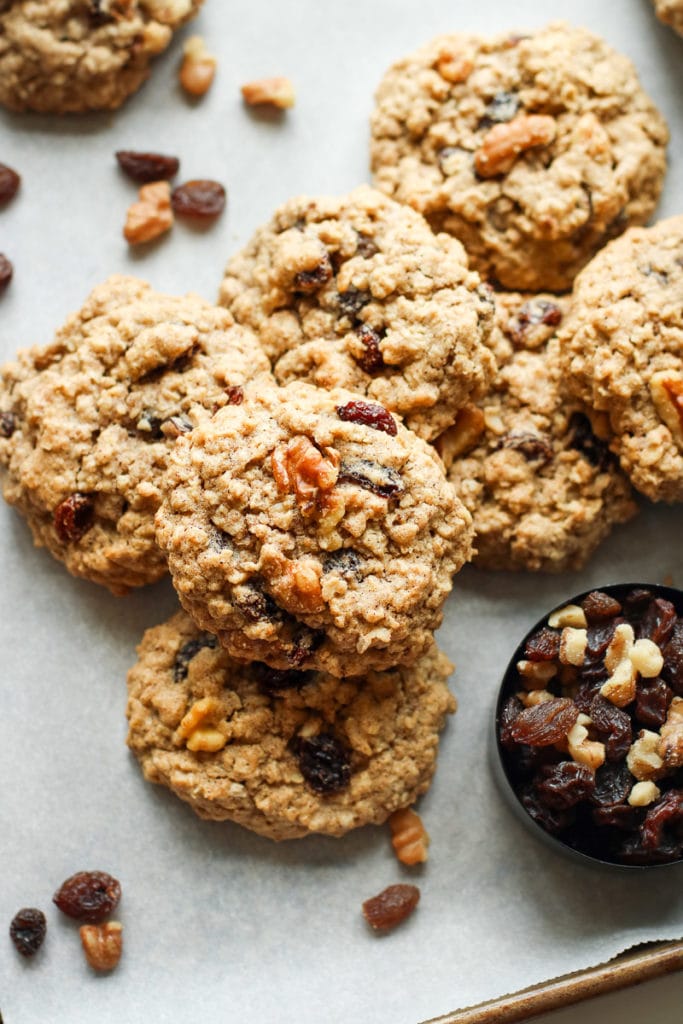 A pile of oatmeal raisin cookies topped with walnuts