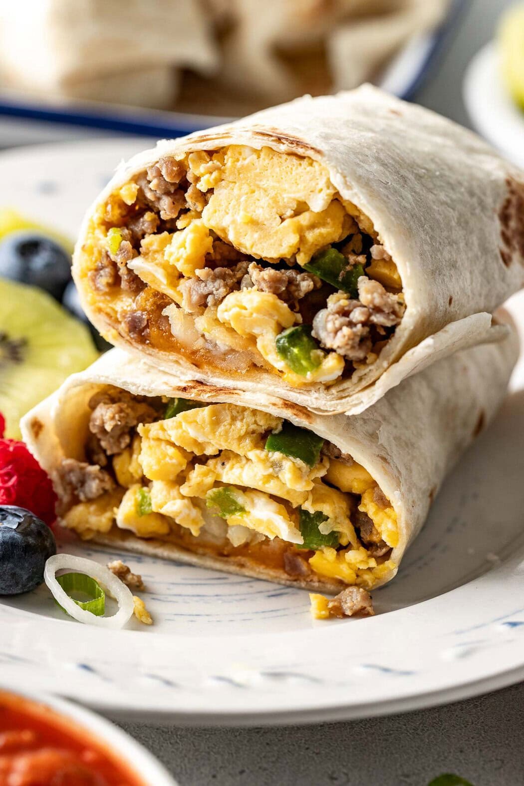 Close up view of a breakfast burrito cut in half and stacked showing the egg and sausage mixture on the inside. 