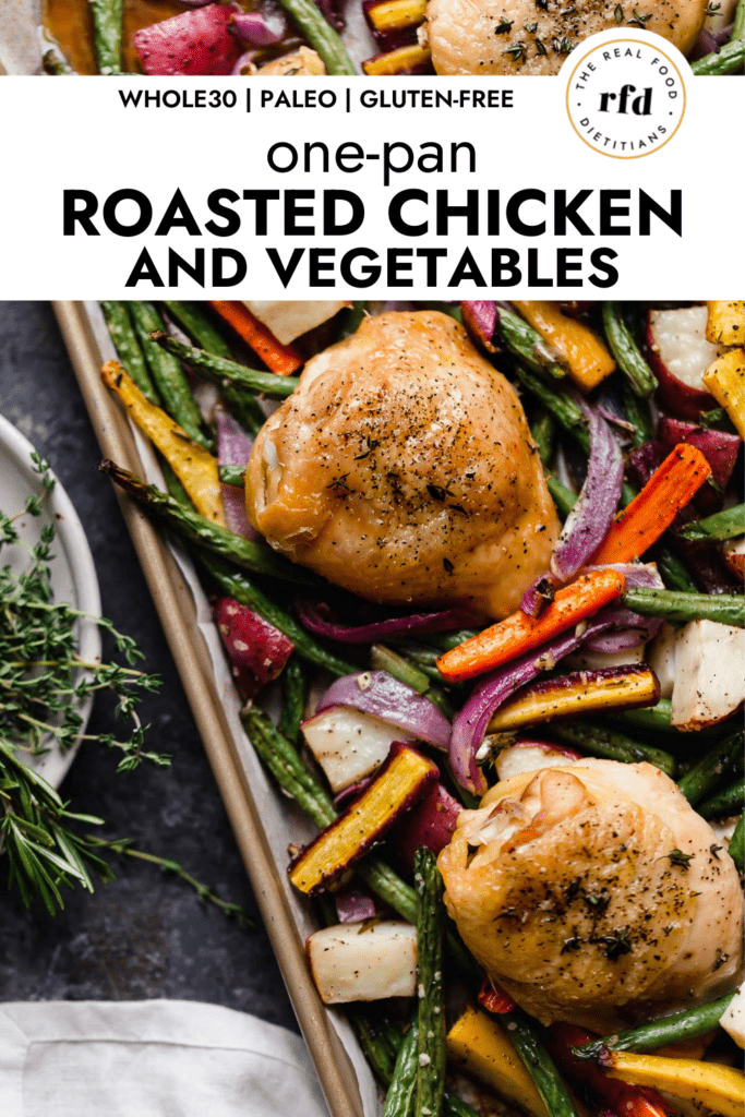 Perfectly roasted chicken thigh topped with cracked black pepper and fresh herbs on a sheet pan with roasted vegetables.