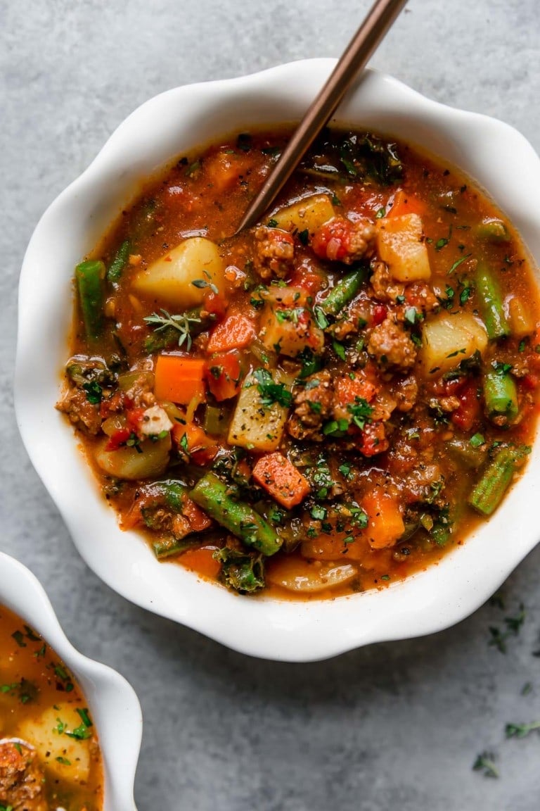 Overhead view of a bowl of Crockpot Hamburger Soup topped with fresh herbs. 