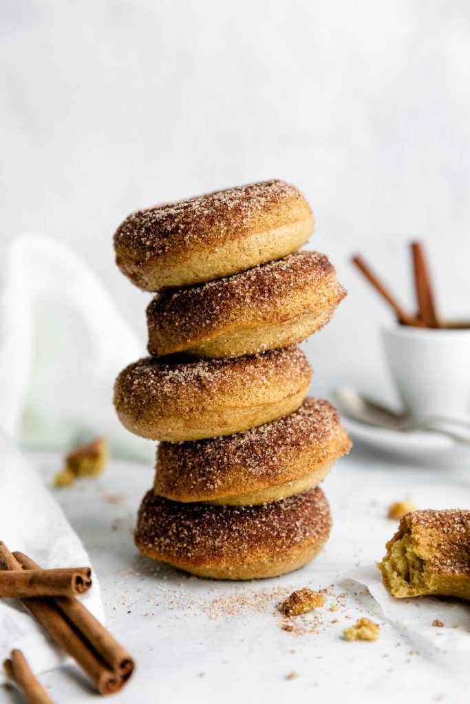 A tall stack of five gluten-free baked donuts with cinnamon sugar coating on a counter. 