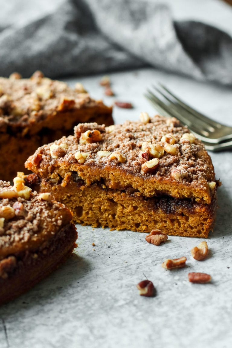 Close up view of a freshly baked and sliced pumpkin coffee cake with a middle layer of buttery cinnamon swirl streusel. 