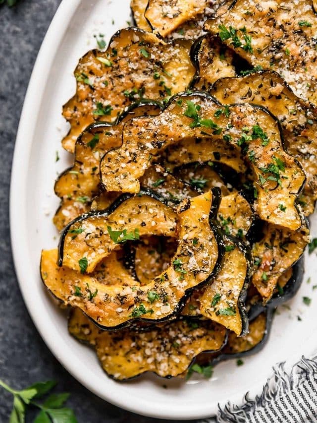 herb-crusted parmesan acorn squash slices baked to golden brown served on a white platter