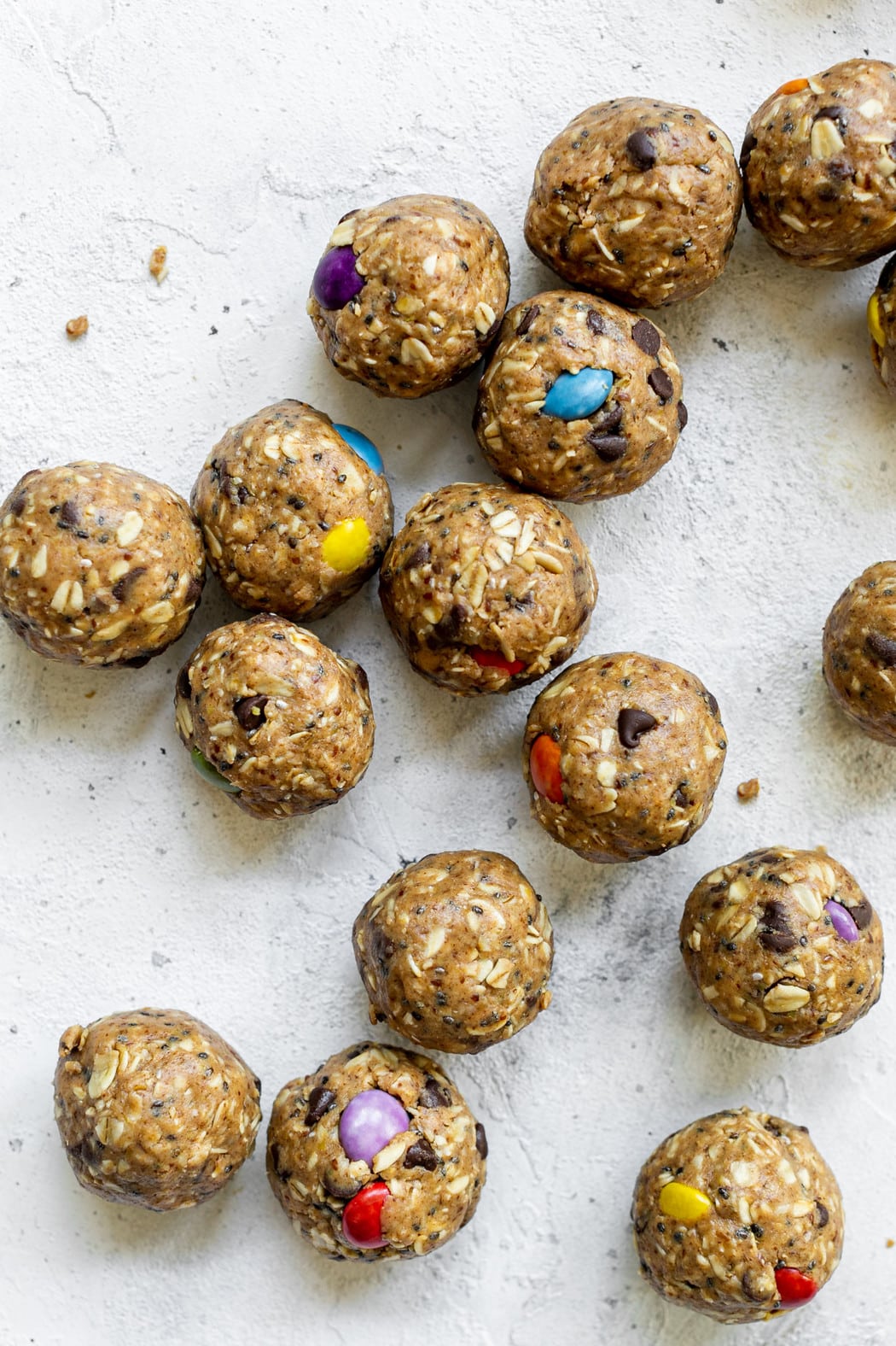 Monster cookie peanut butter energy balls with colorful candy pieces rolled into balls arranged on counter. 