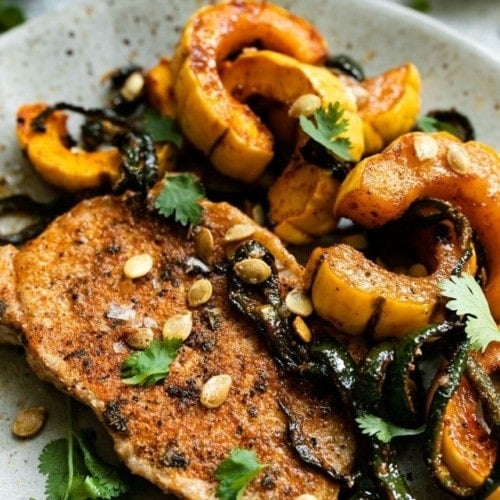 Oven Baked Pork Chops with roasted delicata squash plated on a ceramic plate