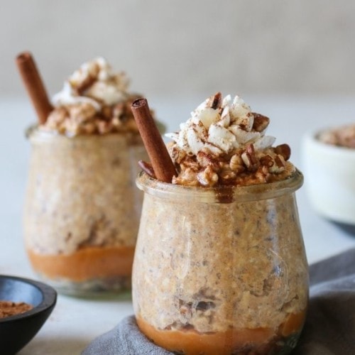 Two jars of pumpkin overnight oats topped with whipped cream and cinnamon