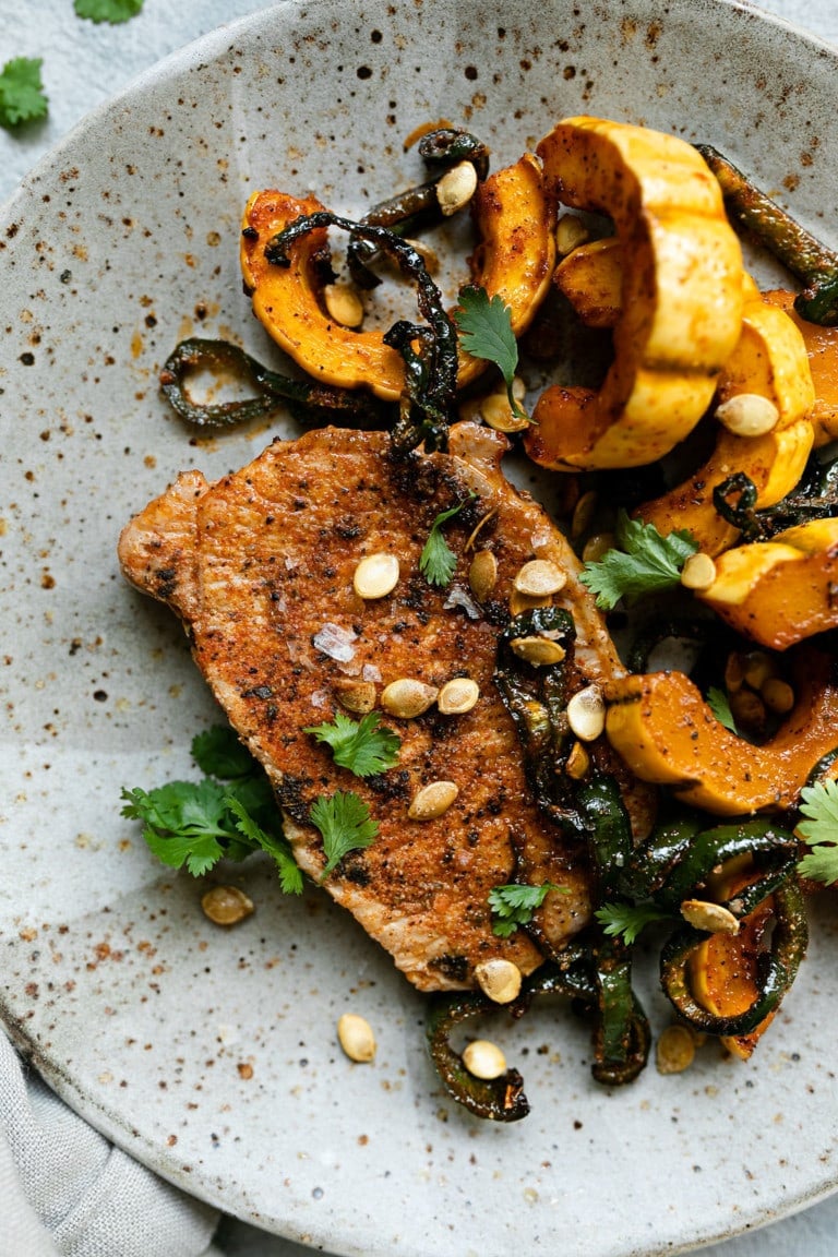 Oven-baked pork chops with delicata squash in a bowl.