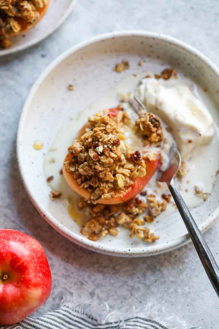 Overhead view of a plate containing a baked apple with crumb topping and vanilla ice cream. 